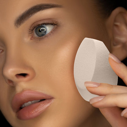 Close-up of a person applying makeup with the Drop of Finesse Makeup Blending Sponge, showcasing its three flat surfaces and round bottom for precision blending.