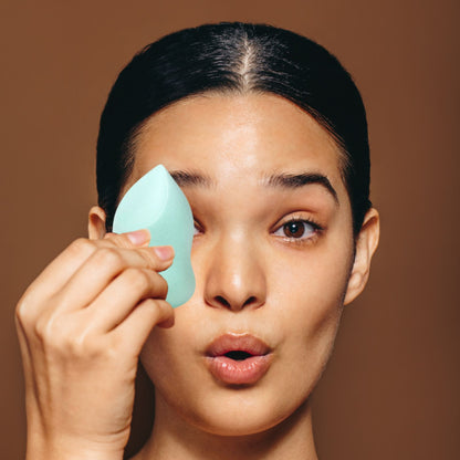 Person using the mint green 4-in-1 Marvel Makeup Blending Sponge to apply makeup on their face