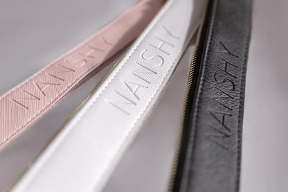 Close-up of Nanshy clear PVC makeup pouches showcasing vegan leather edging in pink, white, and black with golden brass zippers.